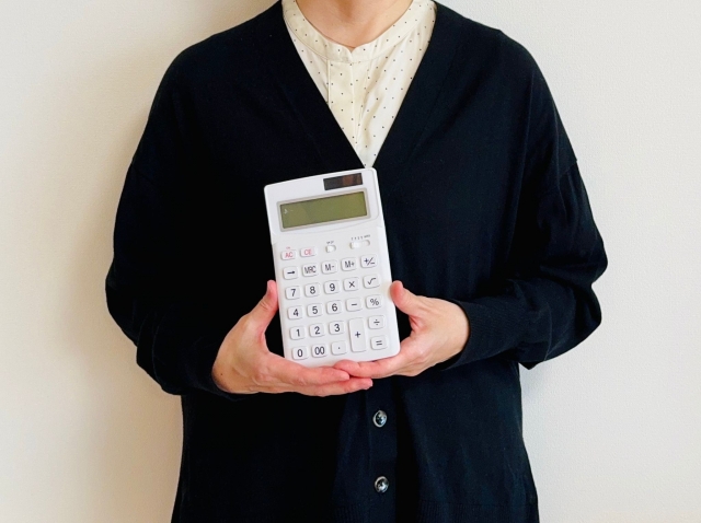 白い電卓を持った黒いトップスの女性