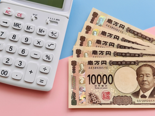 お金(現金5万円)と白い電卓