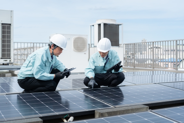 屋上で太陽光パネルを点検する作業員